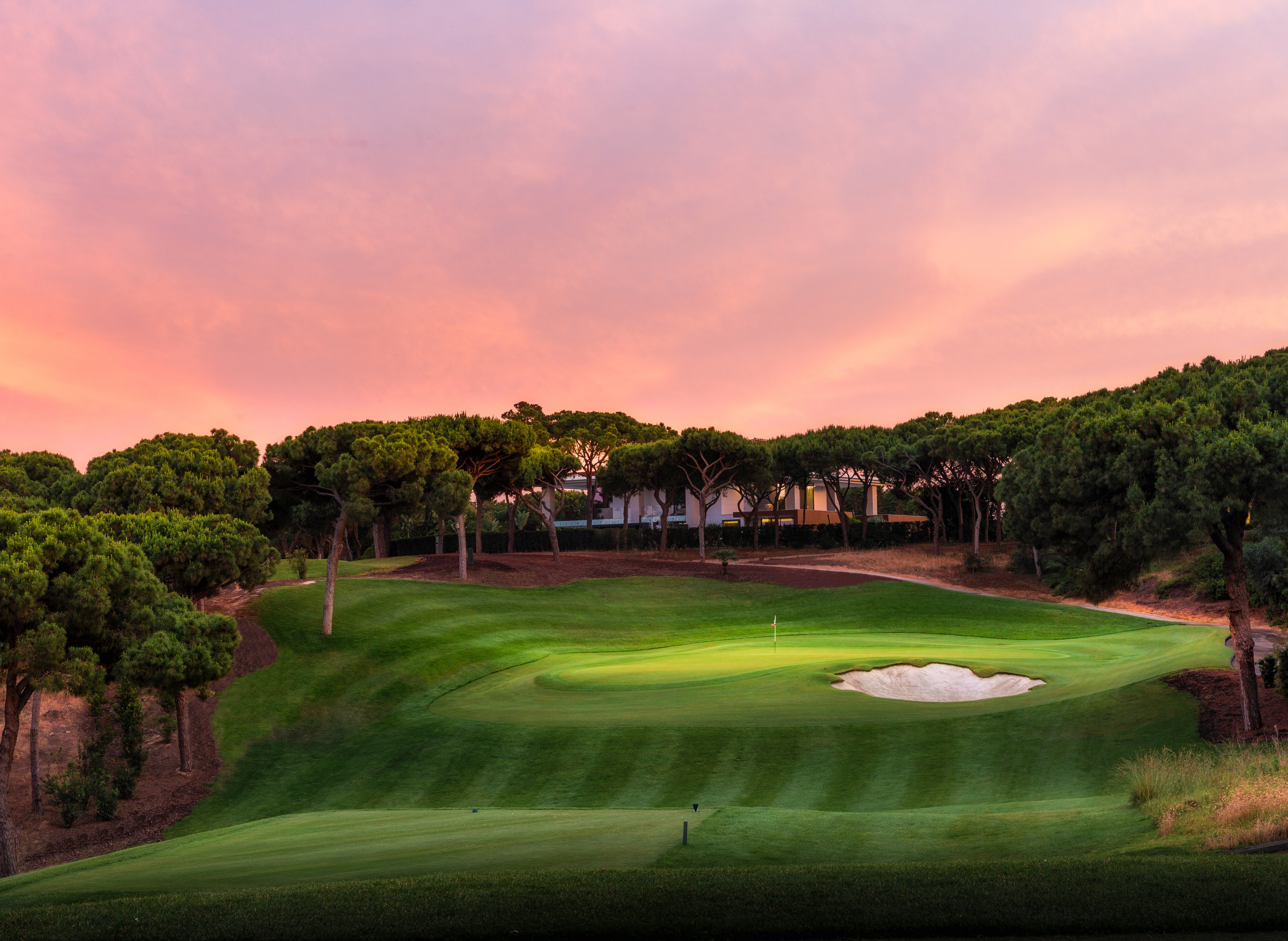Scenic view of the South Course at Quinta do Lago, with fairways overlooking a tranquil lake and the Algarve coastline. Surrounded by lush greenery and set under a clear blue sky, this iconic championship golf course offers a peaceful, coastal golfing experience in Portugal